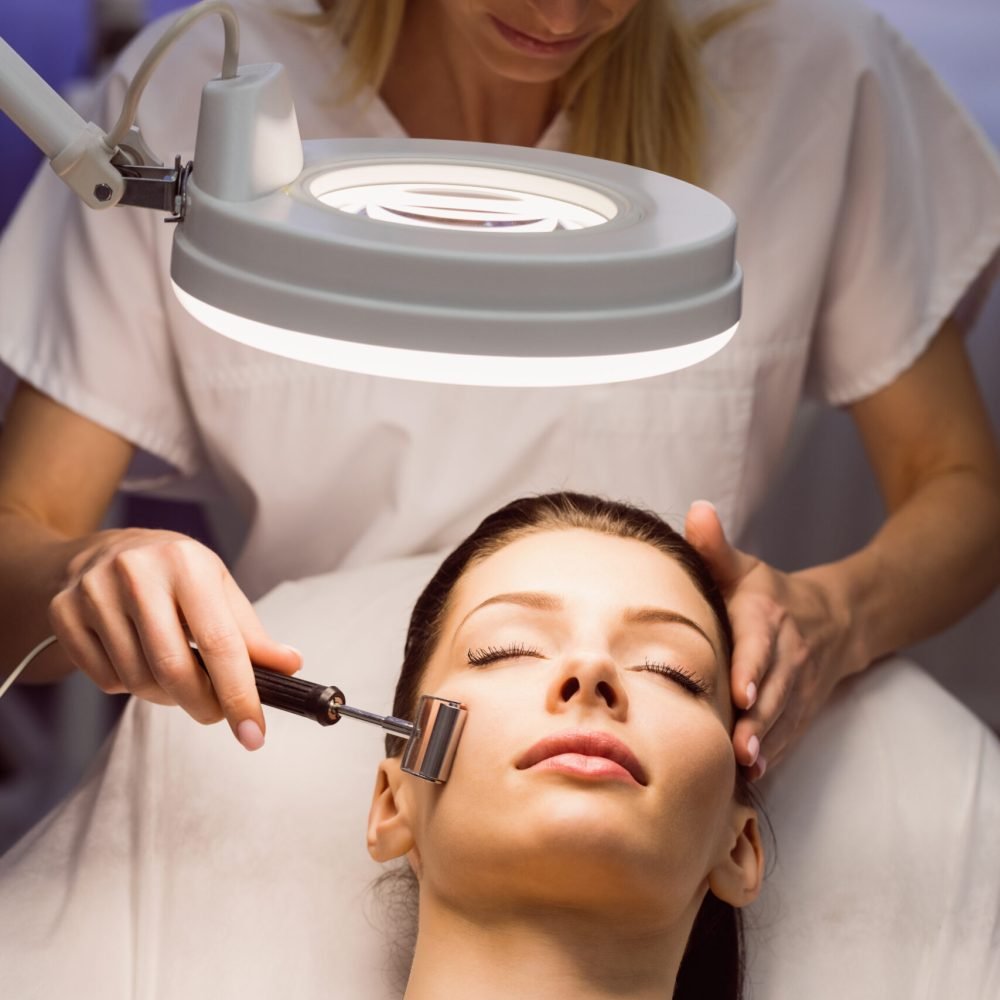 Dermatologist performing laser hair removal on patient face in clinic