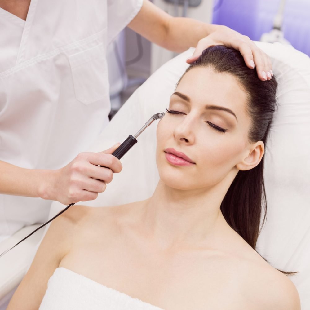 Dermatologist performing laser hair removal on patient face in clinic