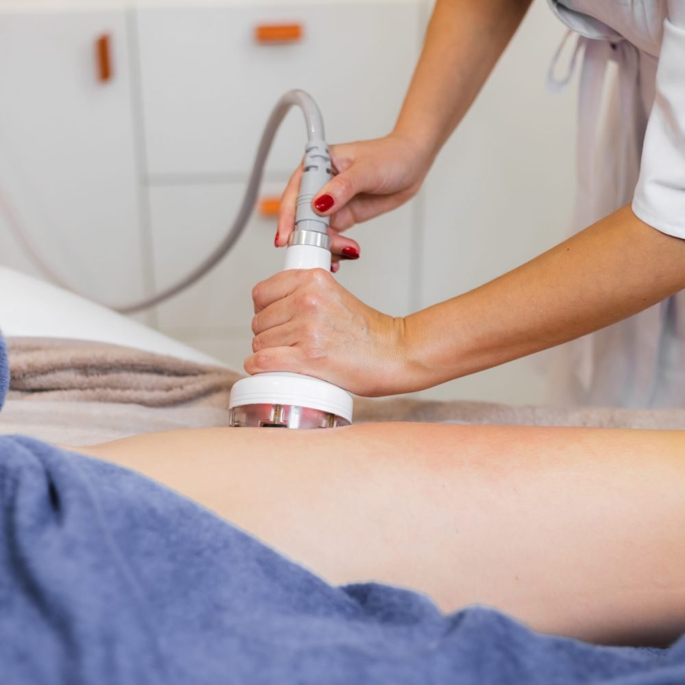 Masseur doing anti-cellulite massage to client in spa beauty salon using oil